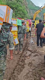 8月6日，河北保定。子弟兵背着物资在泥泞道路中步行50公里，将食物沿路...